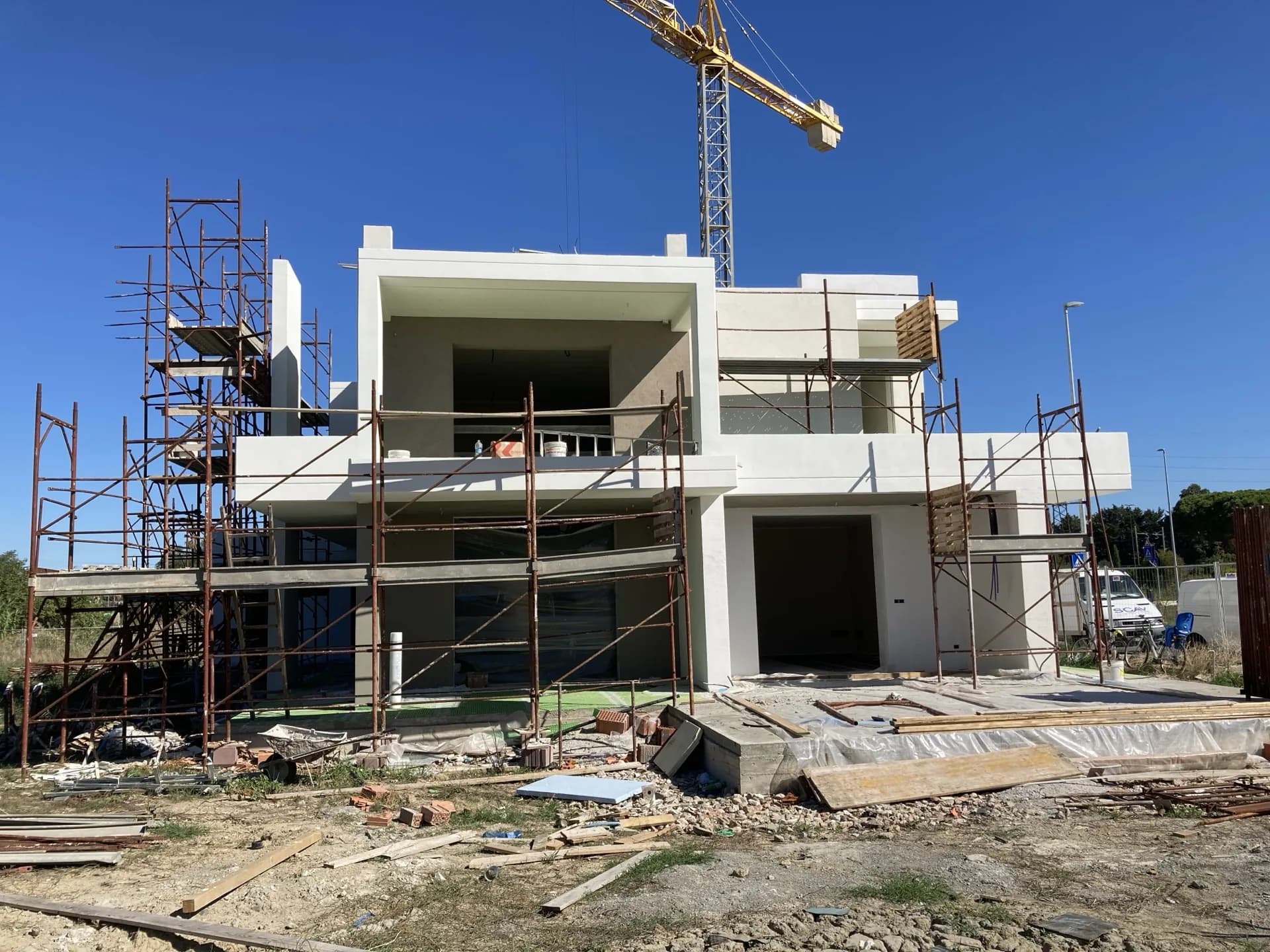 Contemporary villa under construction with scaffolding and tower crane — a design-build villa remodel by Cappelli Interiors